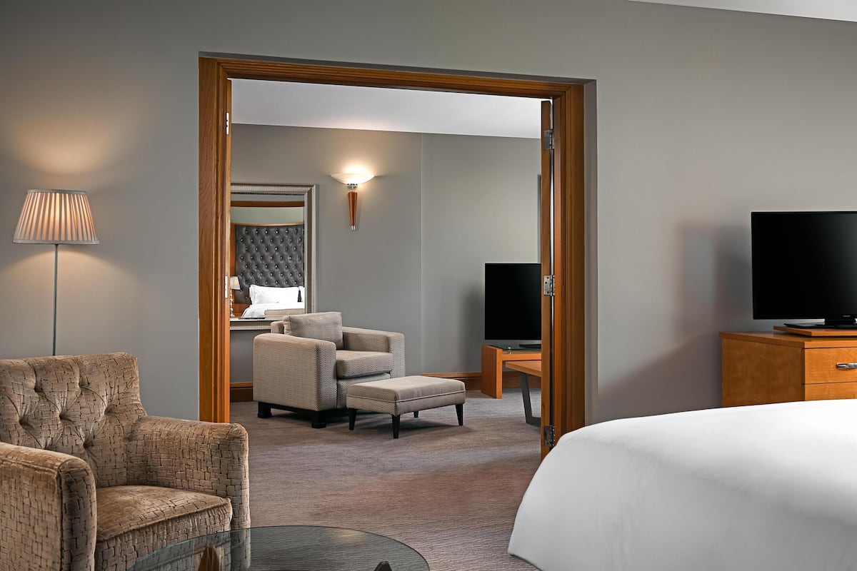 A hotel room with a bed, a television, a desk, a chair, and a lamp.