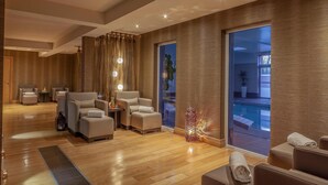 A modern spa room with wooden flooring, multiple seating areas, and a large window overlooking an outdoor area. - Radisson Blu Hotel & Spa, Limerick (Cratloe)
