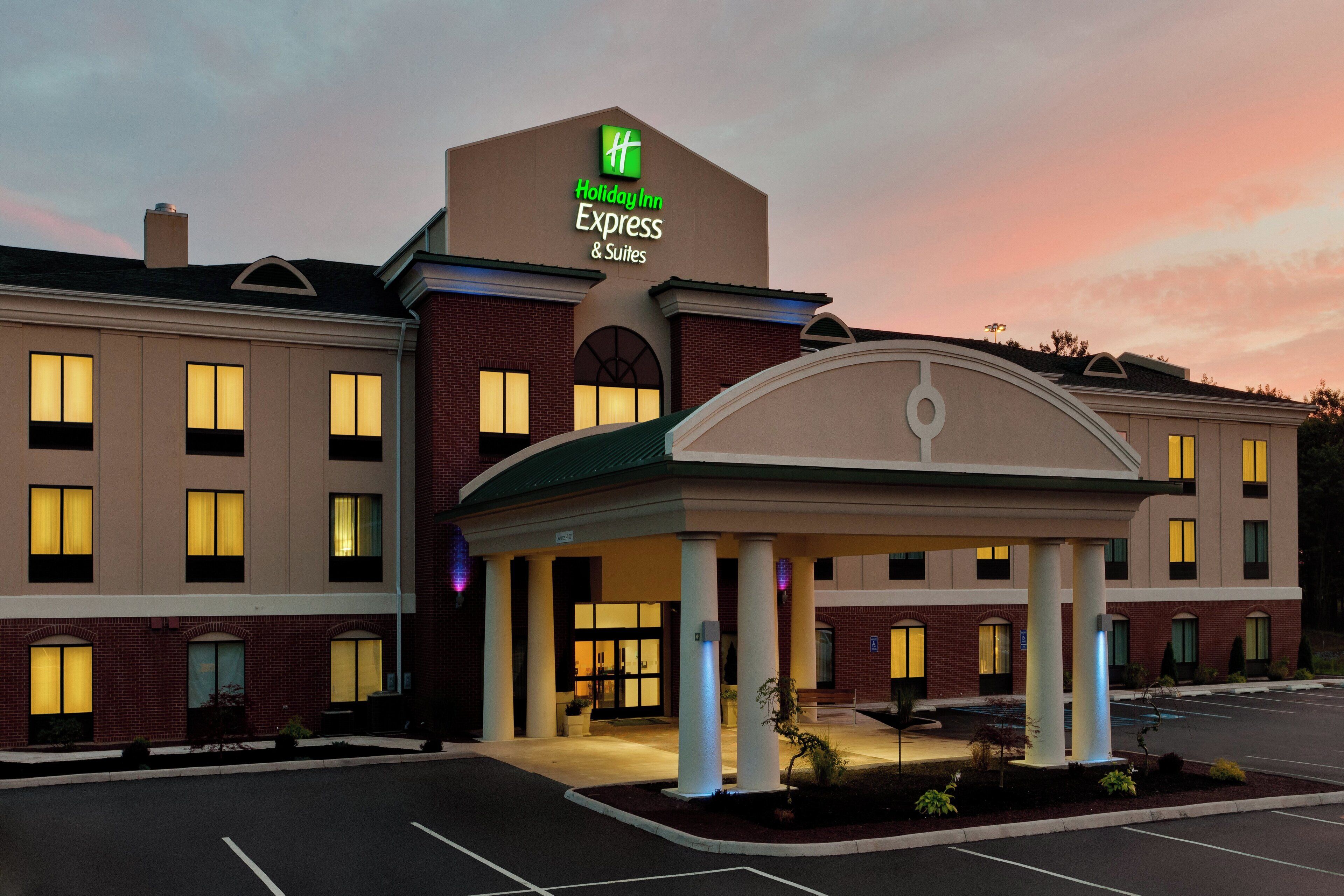 A Holiday Inn Express & Suites hotel with a brick facade, multiple windows, and a covered entrance area.
