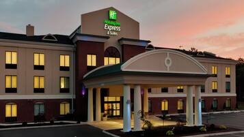 A Holiday Inn Express & Suites hotel with a brick facade, multiple windows, and a covered entrance area.