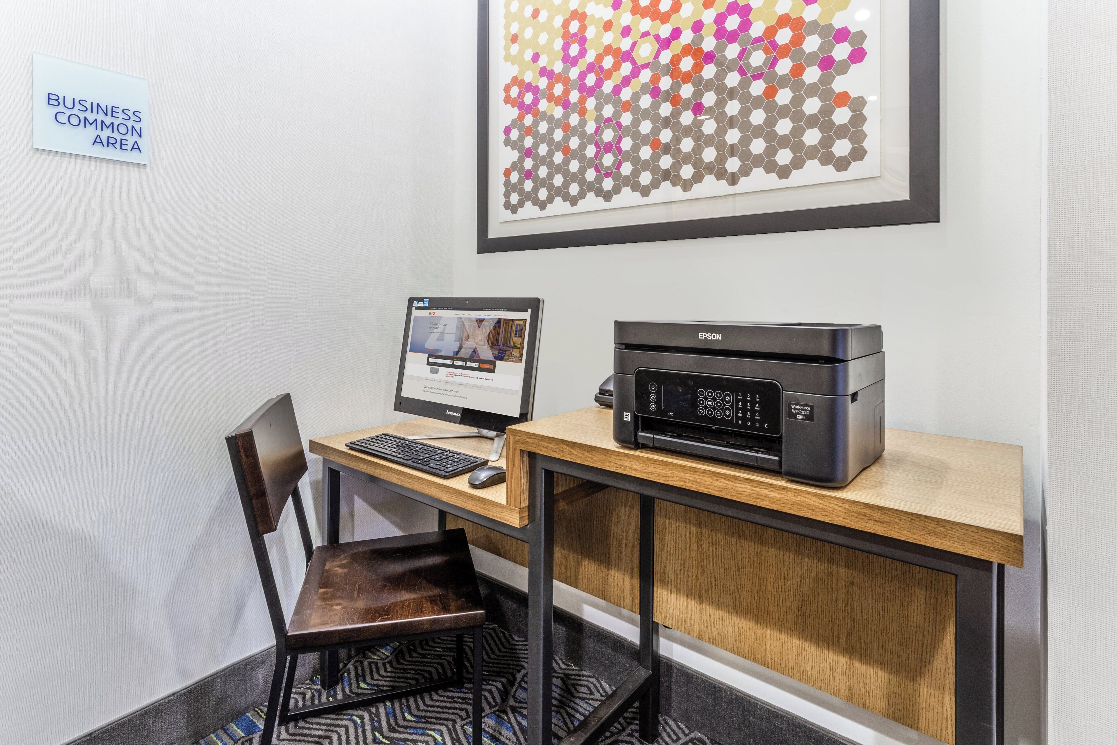 Een werkplek met een computer, een printer en een bord dat een gedeelde ruimte voor bedrijven aangeeft.