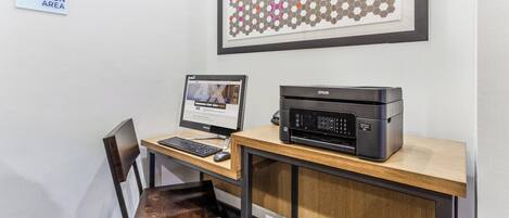 Een werkplek met een computer, een printer en een bord dat een gedeelde ruimte voor bedrijven aangeeft.