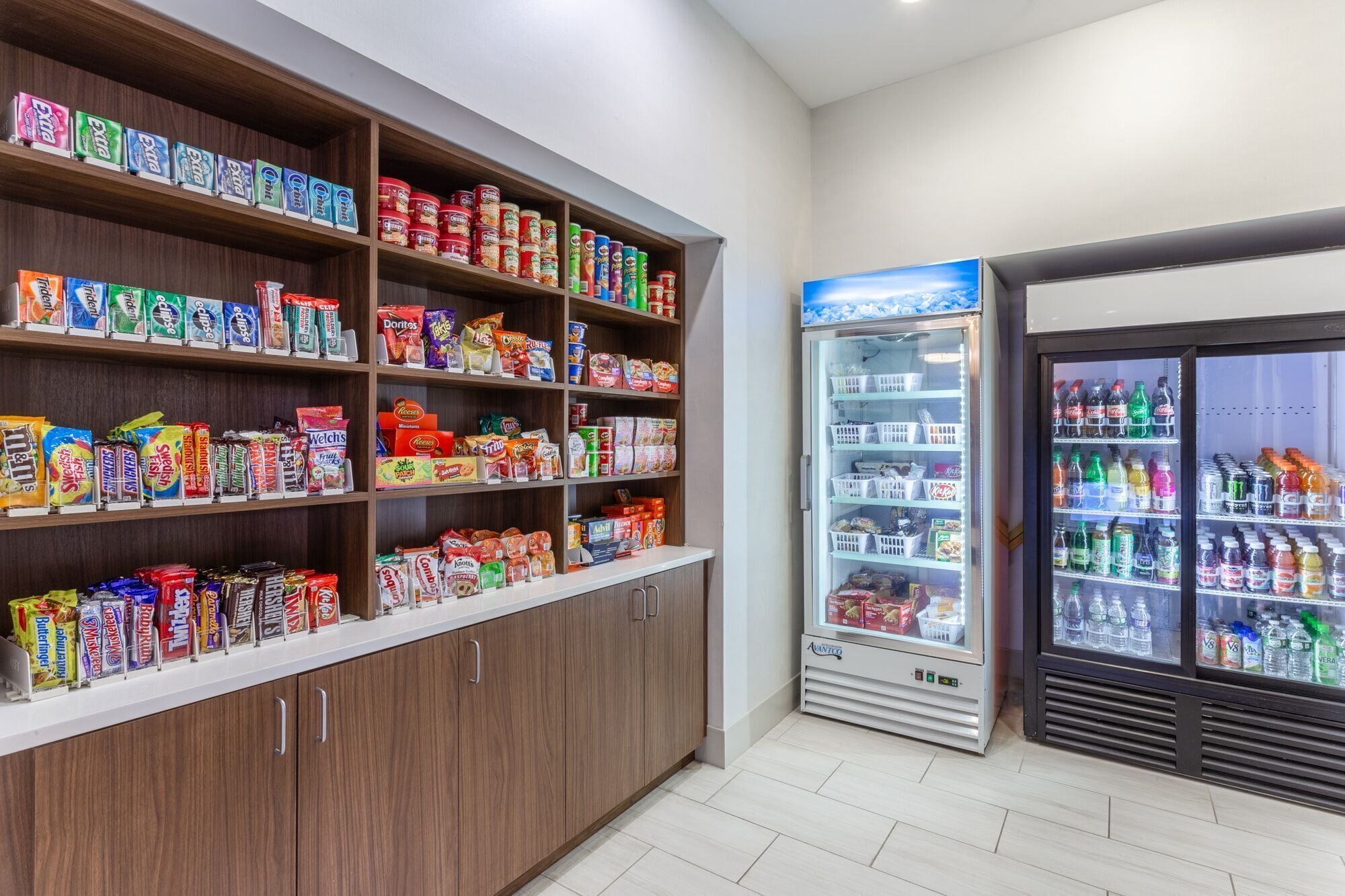 A snack and beverage vending area with multiple shelves stocked with various snacks and a refrigerated section with bottled drinks.