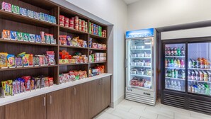 Een automaatruimte voor snacks en drankjes, met meerdere planken vol diverse snacks en een gekoeld gedeelte met flessen.