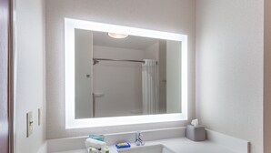Een badkamer met een grote spiegel, een wastafel en een douche.