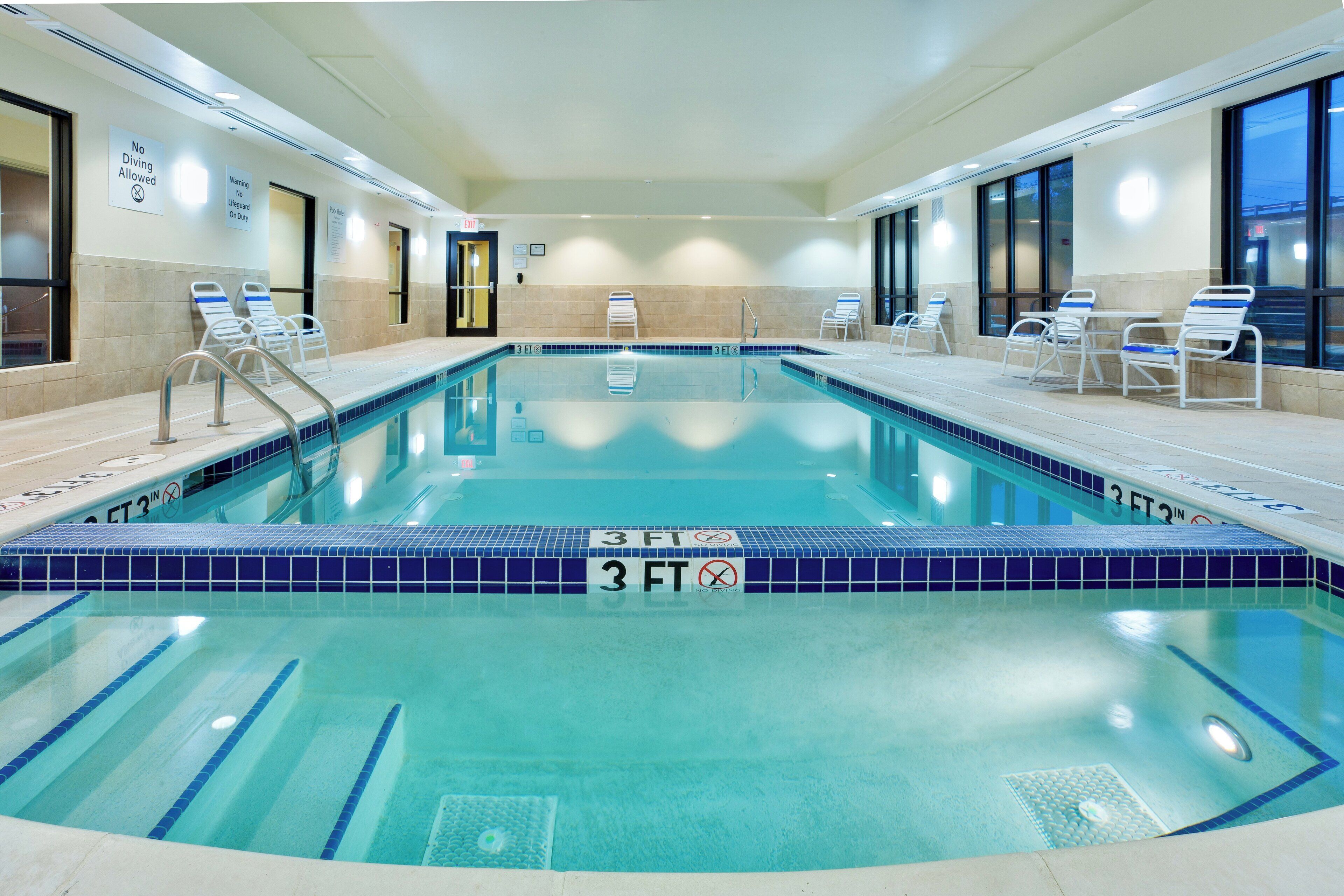 An indoor swimming pool with a 3 FT depth, lounge chairs, and a lifeguard station.