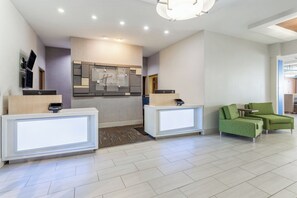 A hotel reception area with two reception desks, a kitchenette, and a seating area with green upholstered chairs. - Holiday Inn Express & Suites White Haven - Poconos by IHG (White Haven)