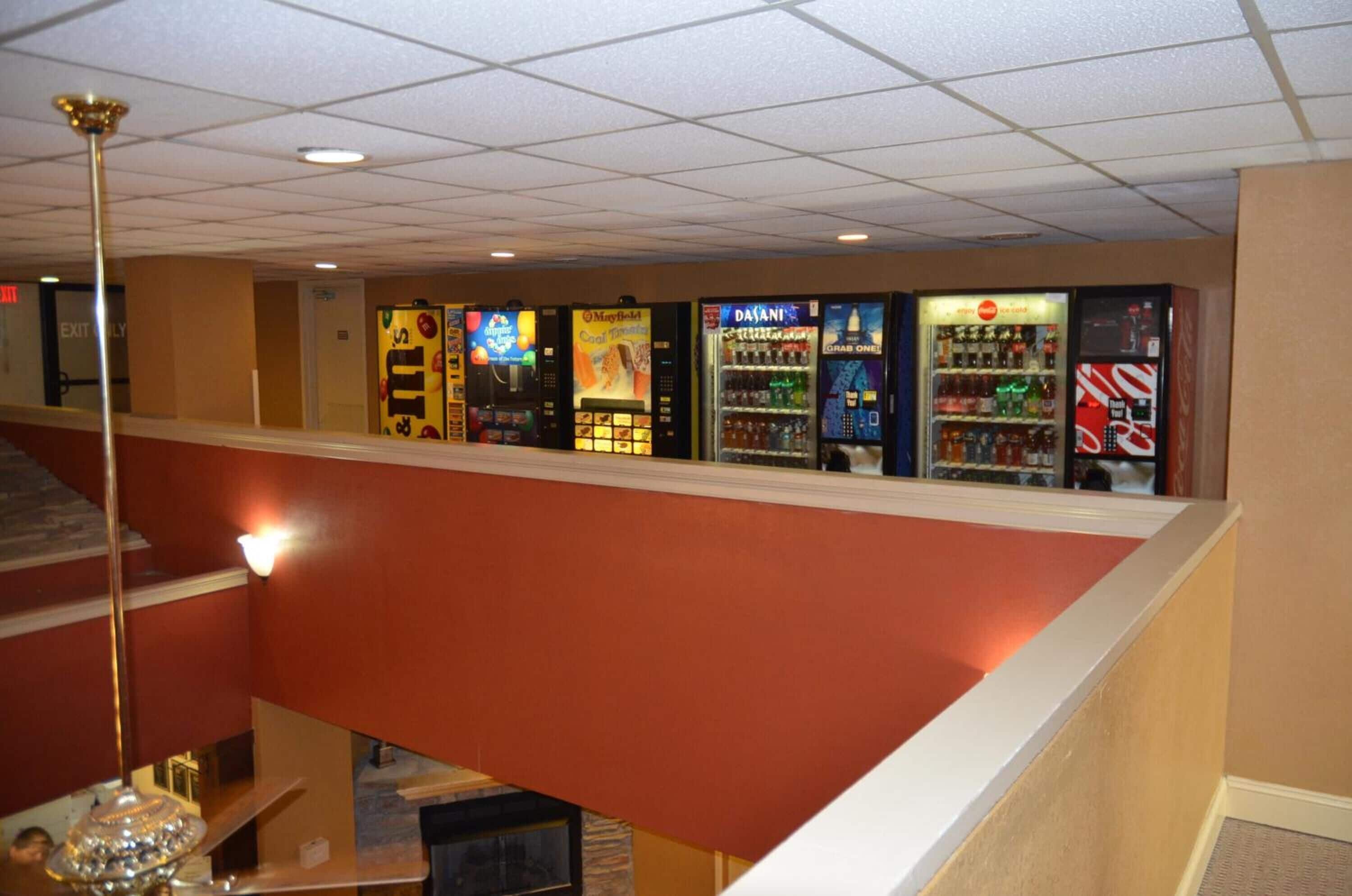 A vending area with various drink machines and a staircase leading to another floor.