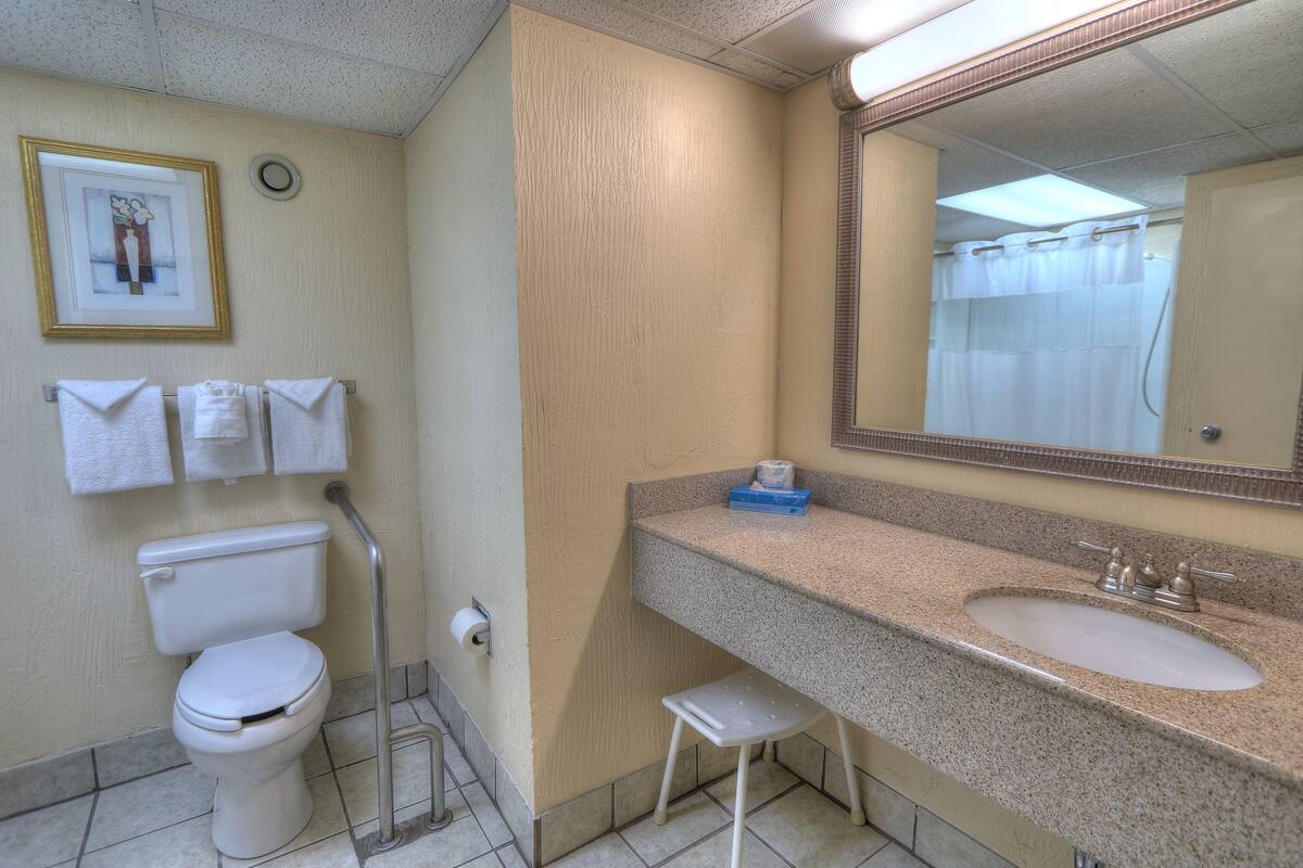 A bathroom with a toilet, sink, and a small stool.