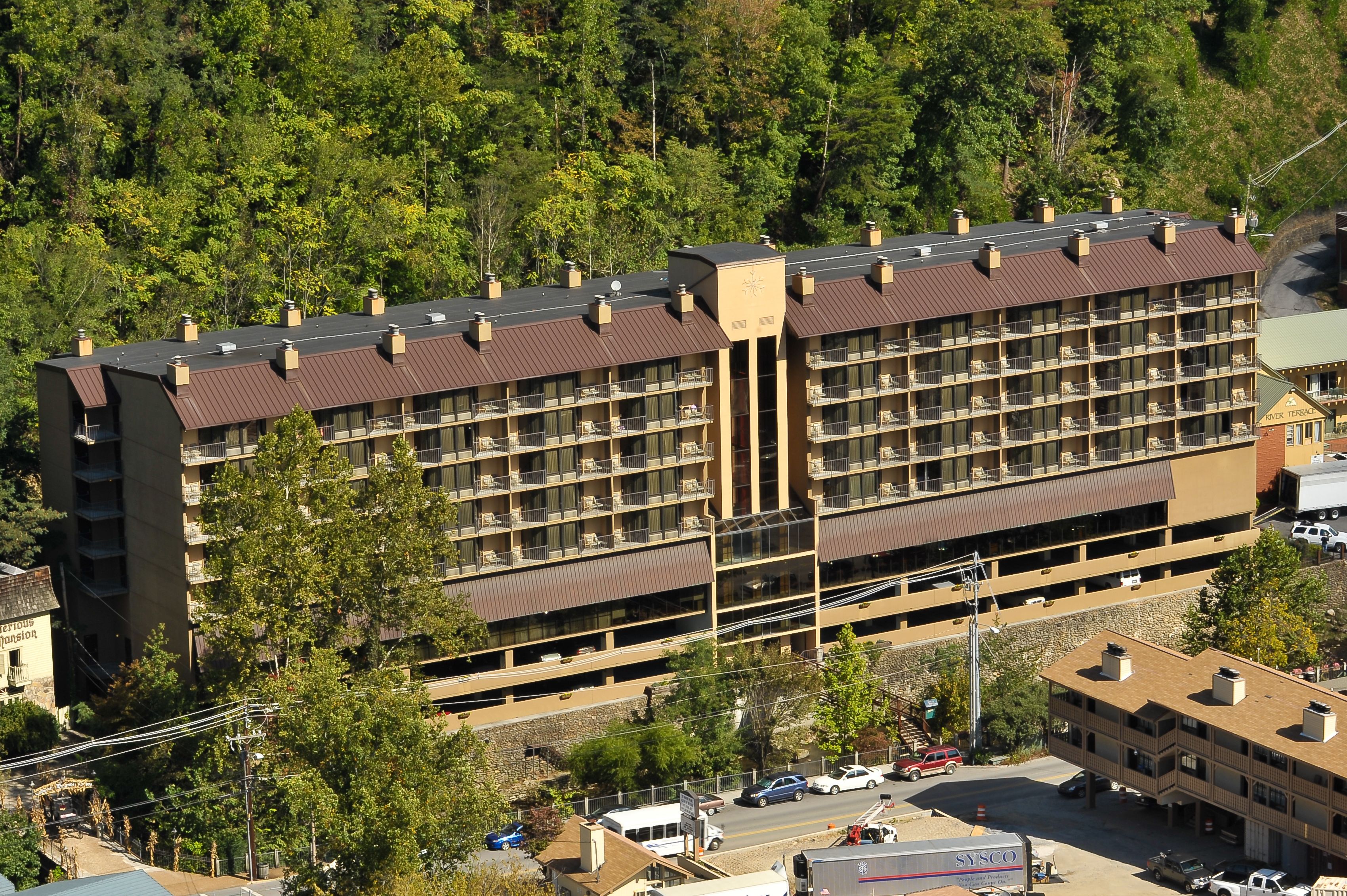 A multi-story hotel with a central courtyard, surrounded by trees.