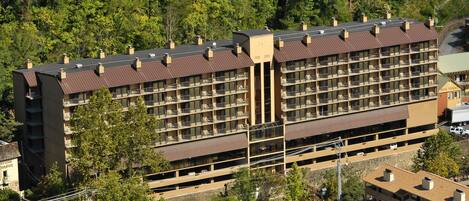 A multi-story hotel with a central courtyard, surrounded by trees.