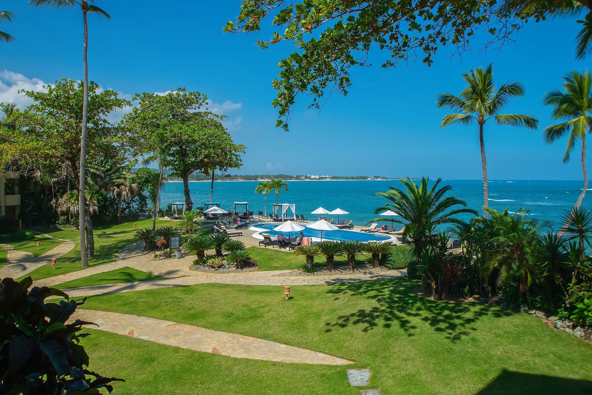 A resort with a pool area, lounge chairs, and palm trees.
