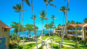 Um resort com palmeiras, área de piscina e vista para o oceano.