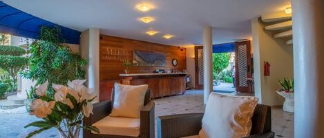 A lobby area with wicker furniture, a reception desk, and a clock on the wall.