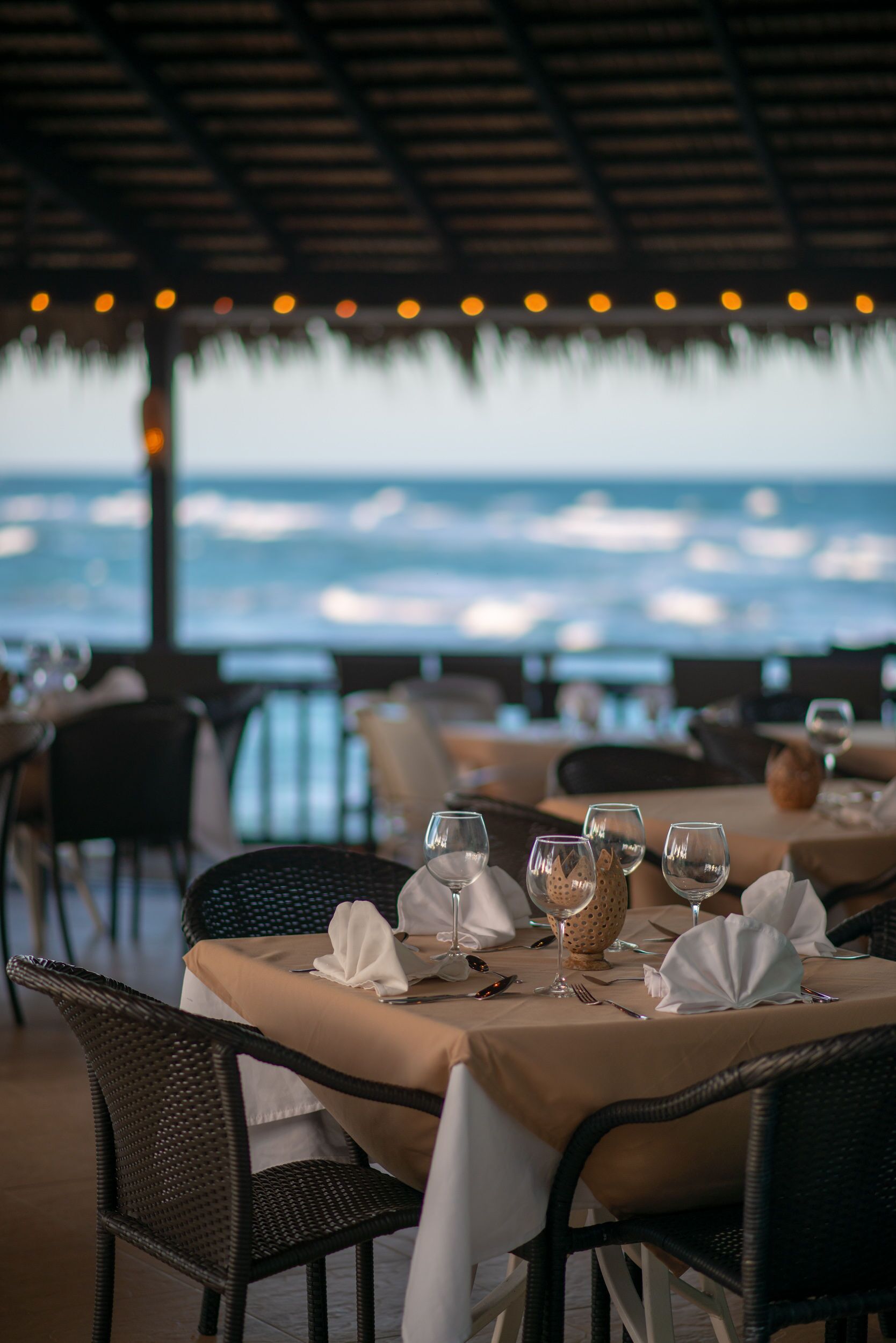 A dining table set with glasses and cutlery, overlooking the sea.