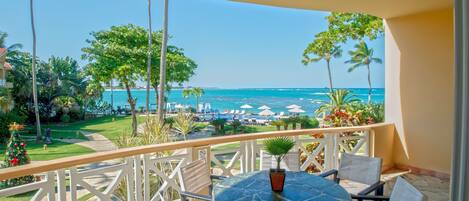A balcony with a view of the ocean, a table with chairs, and a Christmas tree.
