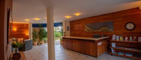 A reception area with a wooden reception desk, a clock, and a sign that reads "VELERO BEACH RESORT".