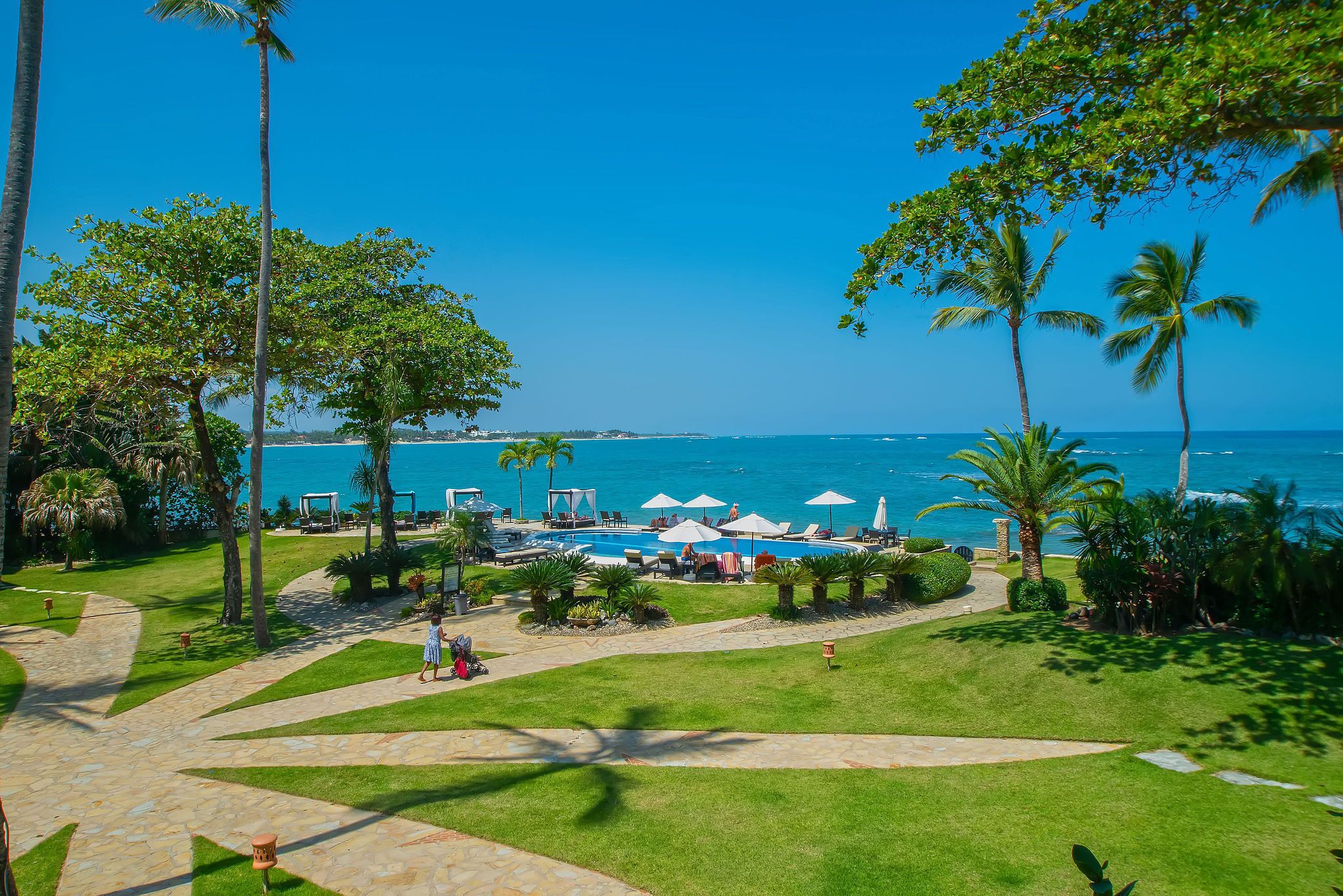 Ein Resort mit Schwimmbad, Liegestühlen und Palmen.