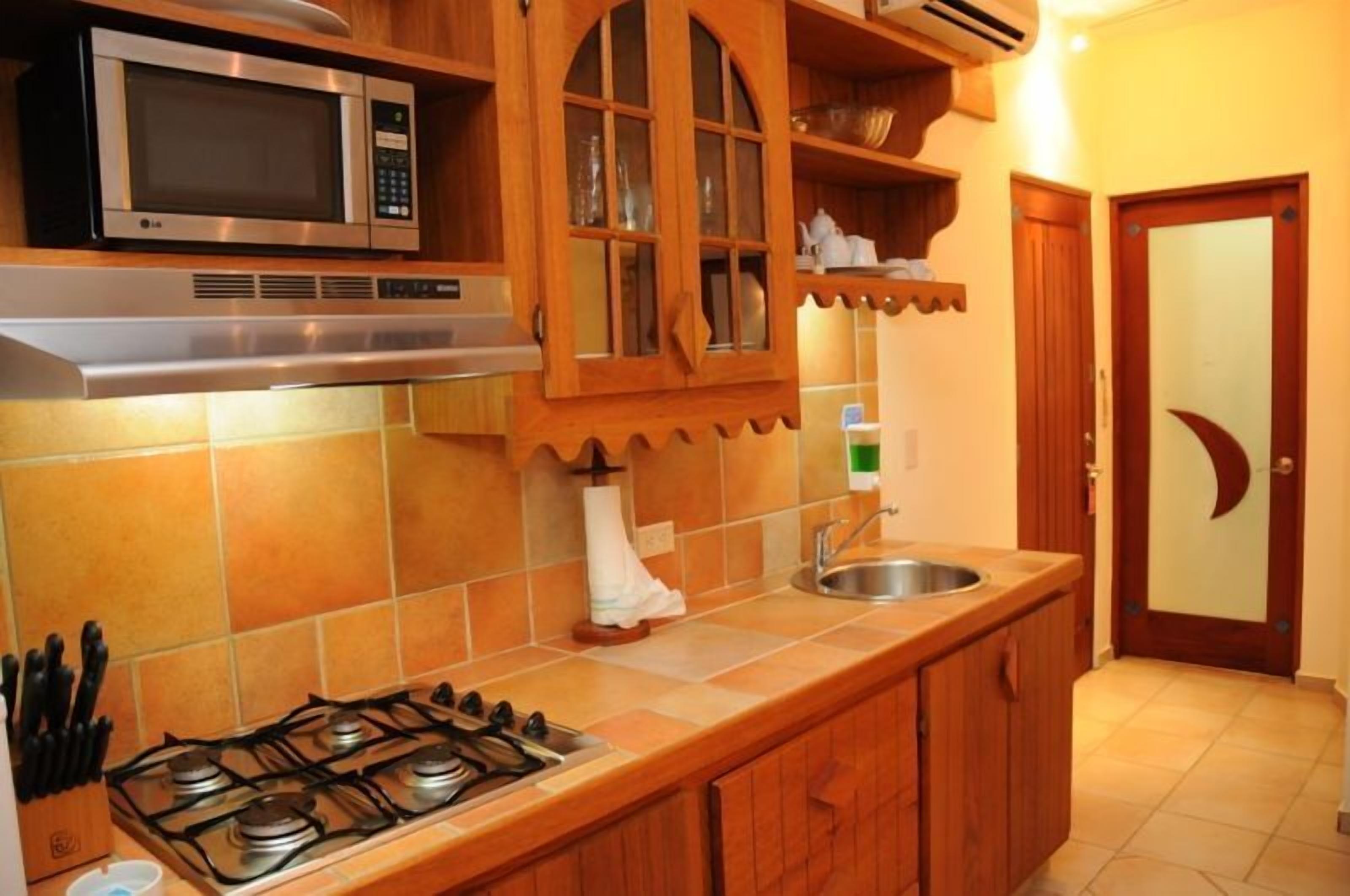 A kitchen with a gas stove, a microwave, wooden cabinets, and a sink.