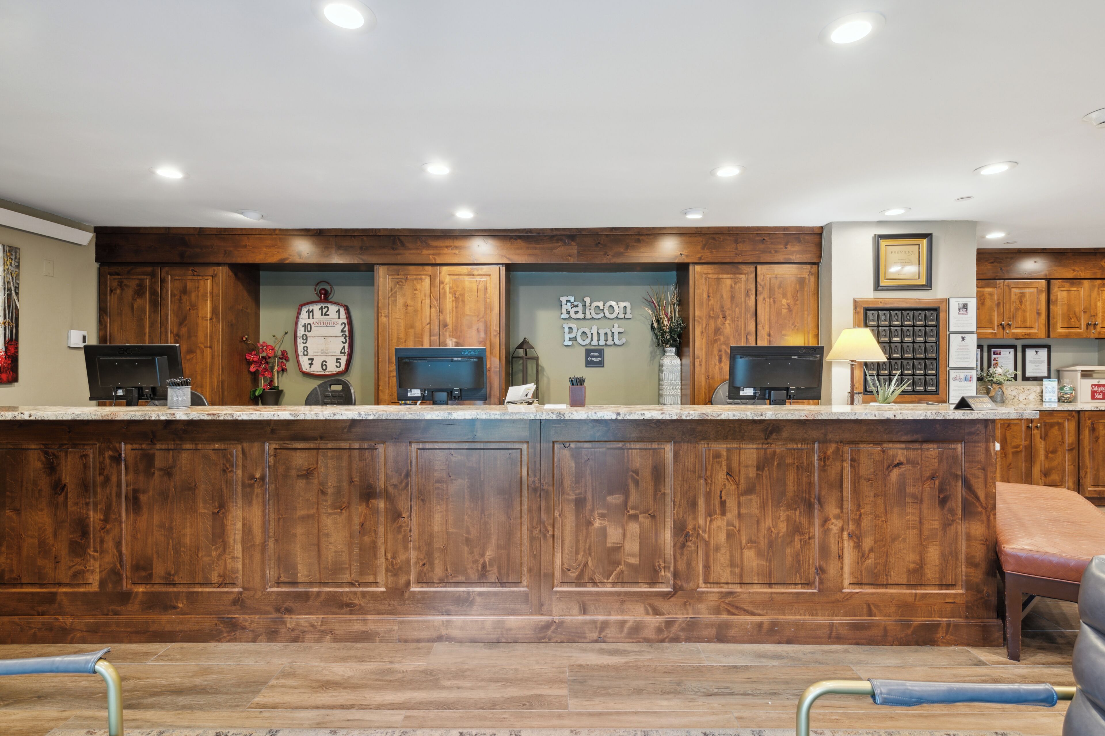 A reception desk with wooden paneling, a clock, and a sign reading "Falcon Point."