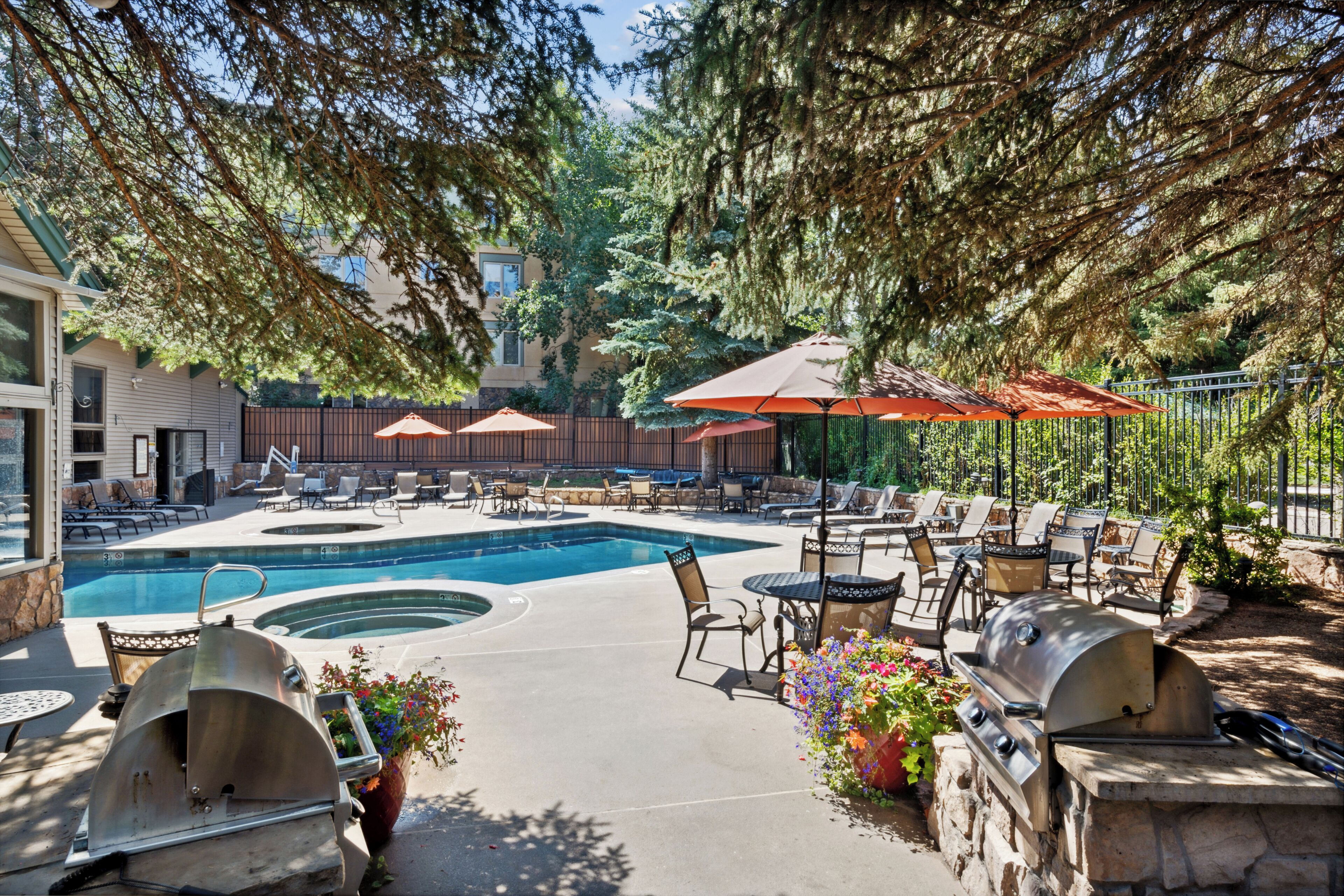 A poolside area with a hot tub, lounge chairs, and barbecue grills.