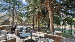 A patio area with wicker furniture, a table, and a view of a road and a fence. - Falcon Point (Avon)