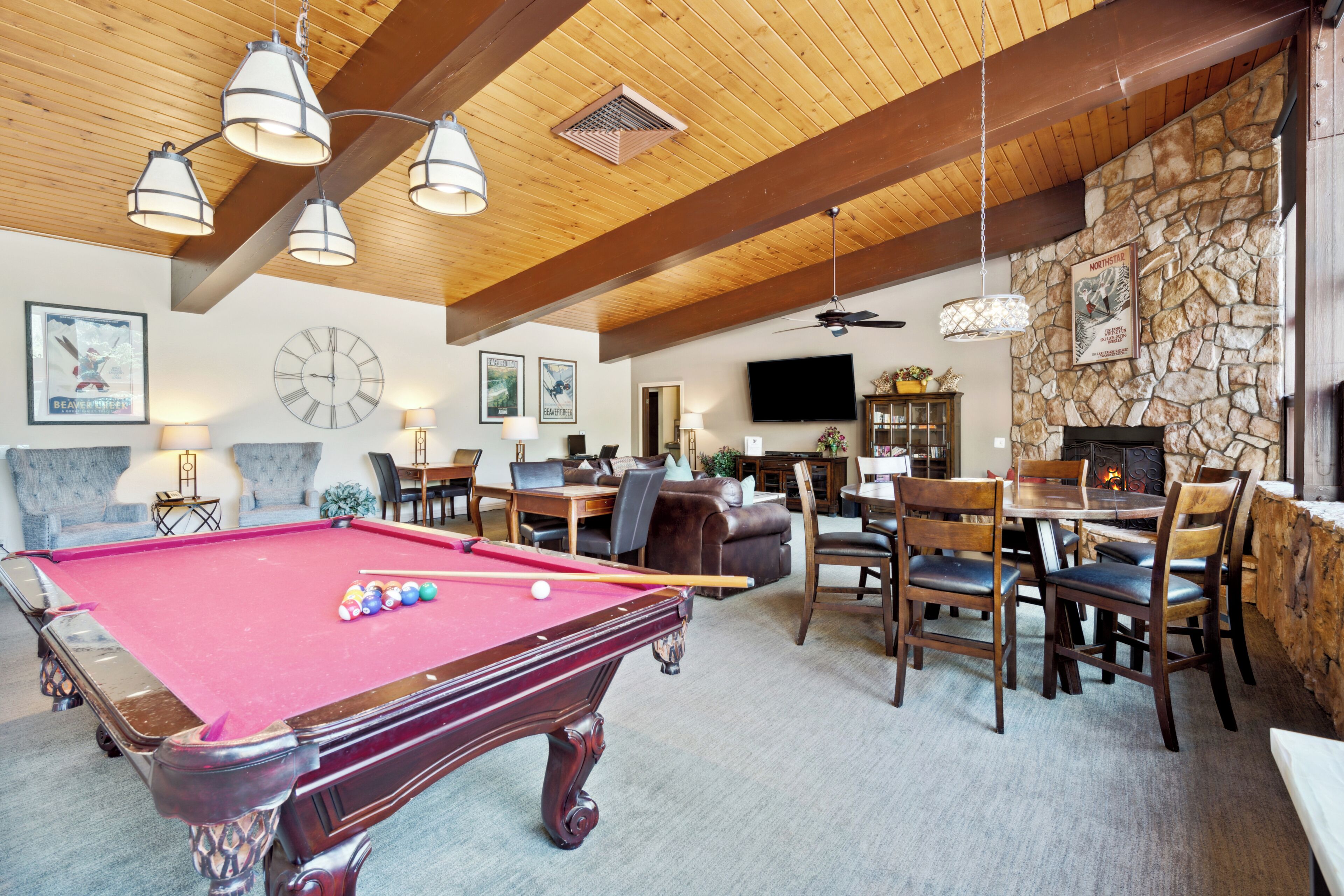 A pool table in a room with wooden beams, stone walls, and a fireplace.