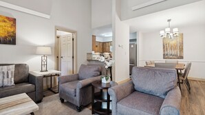 A living room with a sofa, armchairs, a coffee table, and a dining area with a table and chairs. - Falcon Point (Avon)