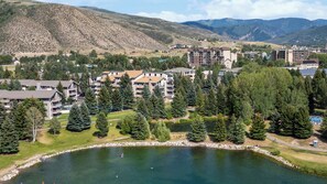 A lakeside resort with multiple buildings, a small dock, and a mountainous backdrop. - Falcon Point (Avon)