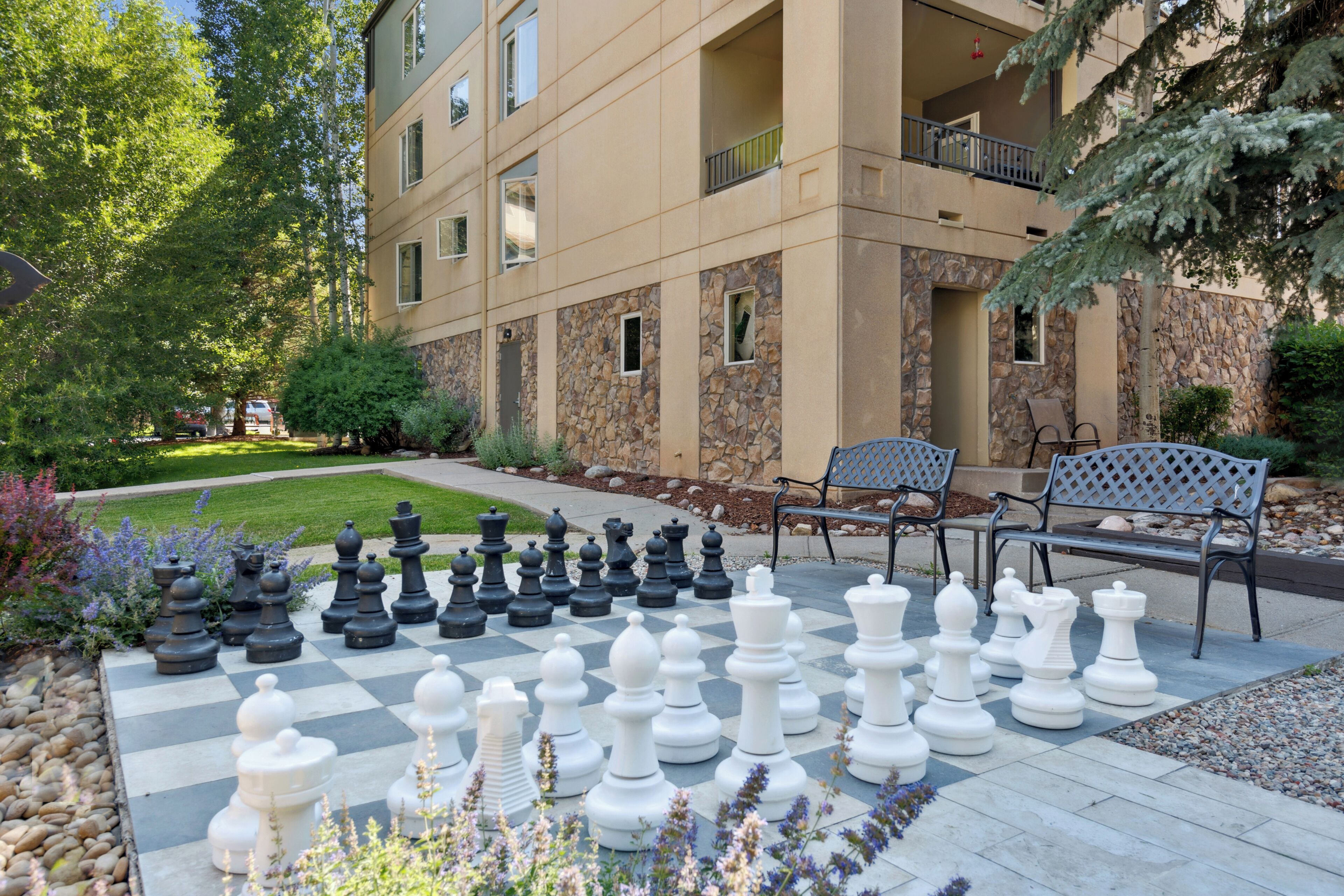 A large outdoor chessboard set up in a courtyard with a building in the background.