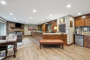 A modern kitchen with a stone accent wall, wooden cabinets, and a built-in island with seating. - Falcon Point (Avon)
