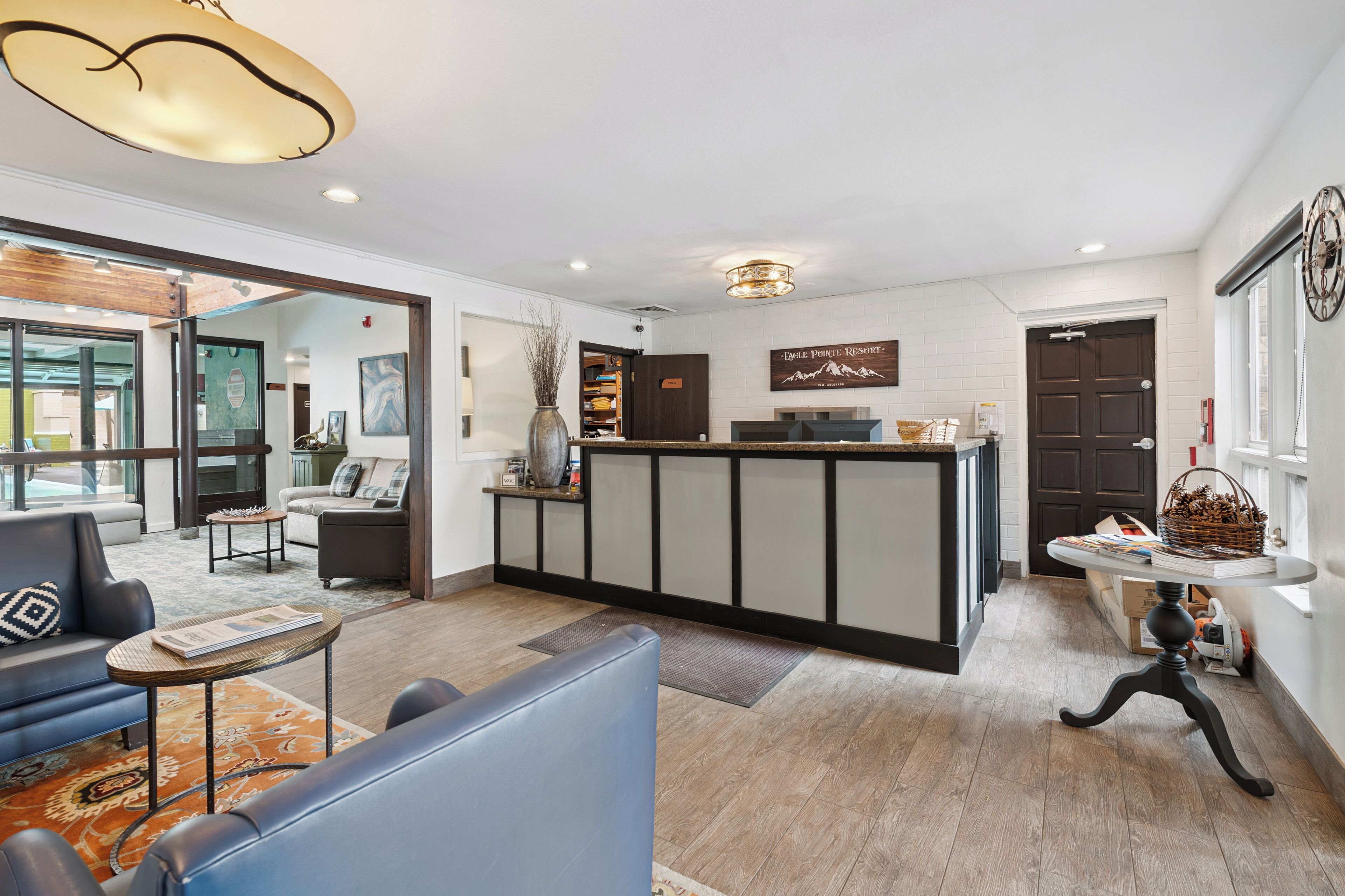 A modern hotel lobby with a reception desk, seating area, and a view of the outside.