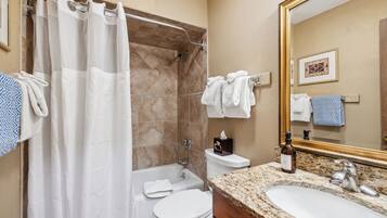 A bathroom with a shower, toilet, sink, and a large mirror.