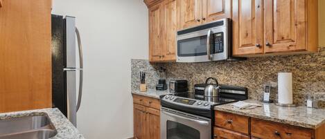 A kitchen with wooden cabinets, stainless steel appliances, granite countertops, and a built-in oven.