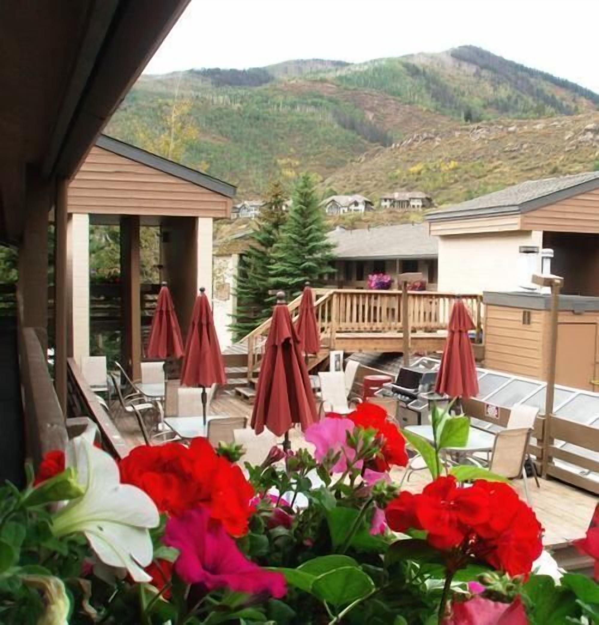 A patio area with outdoor seating and umbrellas, overlooking a mountainous landscape.