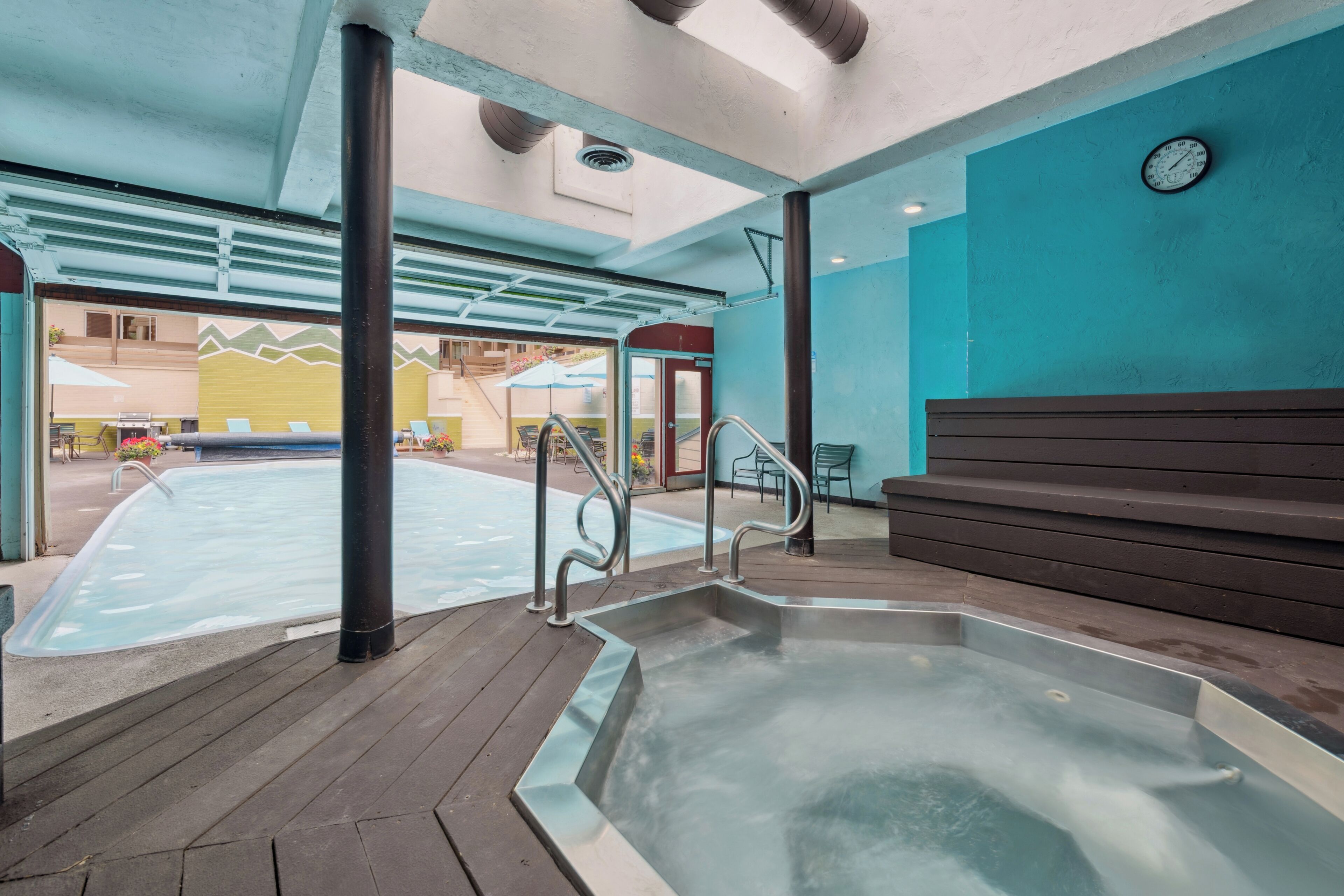 A hot tub area with a wooden deck, metal railings, and a clock on the wall.