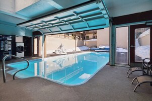 An indoor swimming pool with a glass enclosure, a Pepsi vending machine, and a view of the snowy outdoors.