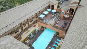 A hotel with a rooftop pool, outdoor seating, and a covered patio area.