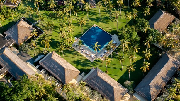 An aerial view of a resort with a central swimming pool, palm trees, and a beach. - Alila Manggis, Bali (Manggis)