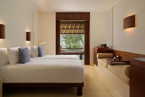 A bedroom with a bed, a sofa, a small table, and a window with a view of trees.