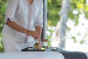 A person in a white shirt pouring a liquid from a bottle into a container on a table.