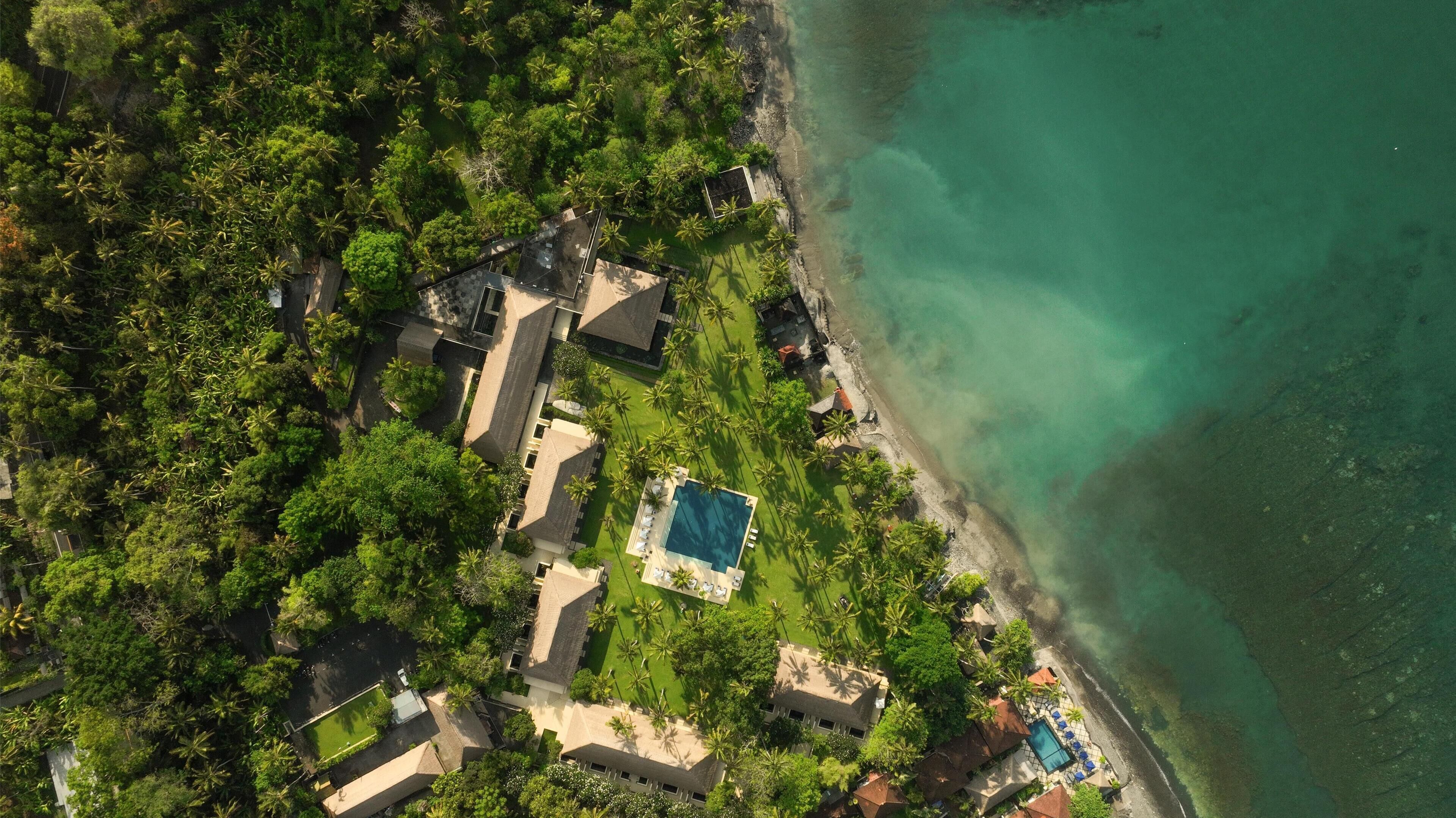 An aerial view of a resort with multiple buildings, a swimming pool, and a beach.