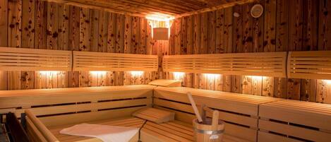 A sauna with wooden benches and a central heating element.