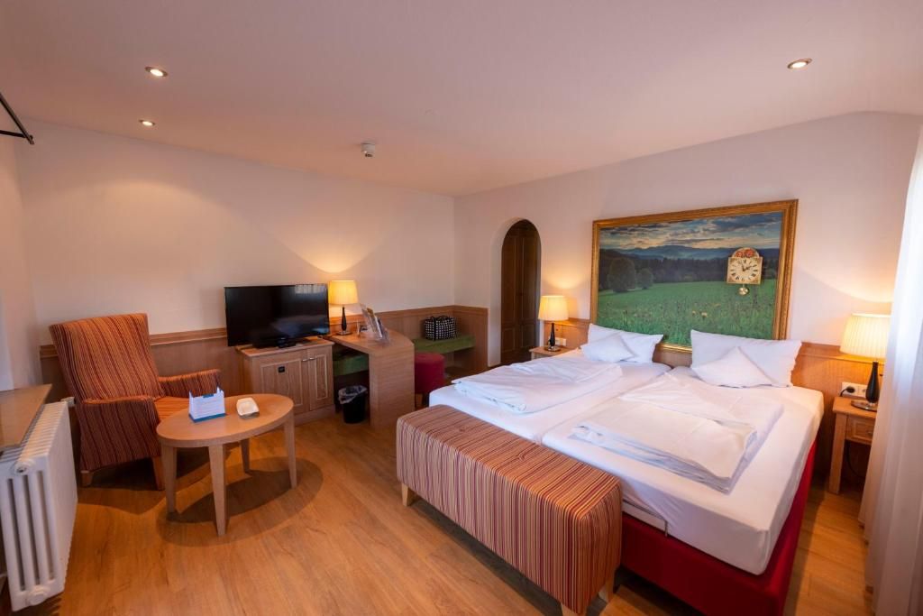 A hotel room with a bed, a TV, a desk, and a chair.