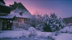 Une maison traditionnelle à colombages, entourée d’un paysage enneigé.