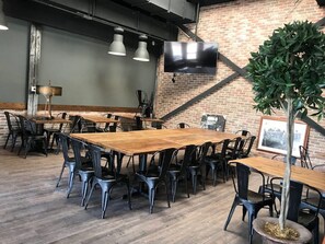 L’intérieur d’un restaurant avec des murs en briques, des tables en bois et des chaises noires.