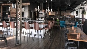 A modern bar area with stools, a counter, and hanging lights. - Tapestry by Hilton The Peery Salt Lake City Downtown, UT (Salt Lake City)