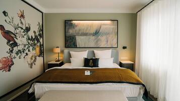 A hotel room with a large bed, two bedside tables, a wall-mounted painting, and a window with curtains.