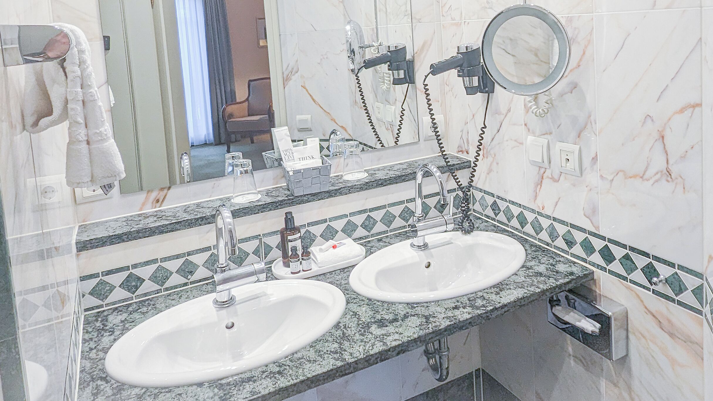 A bathroom with two sinks, a mirror, and a towel rack.