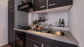 A modern kitchen with dark cabinets, a stainless steel sink, and a built-in oven.